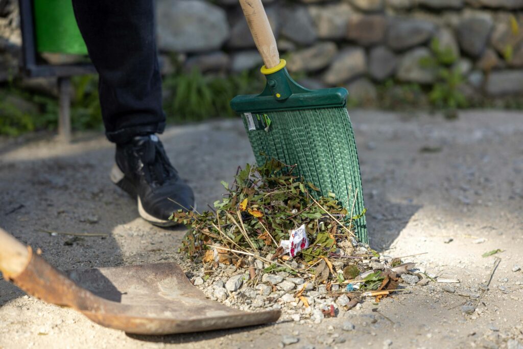 Close-up of a person raking leaves and debris outdoors.